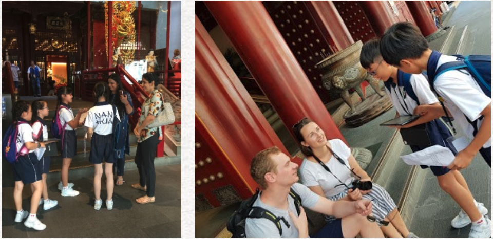 Students in uniforms interact with tourists near large red columns of a traditional Chinese temple.